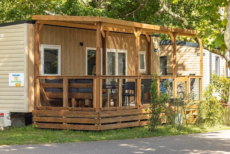 Stacaravan met houten gevel en een overdekte veranda met loungebank en eettafel op Camping Bijela Uvala