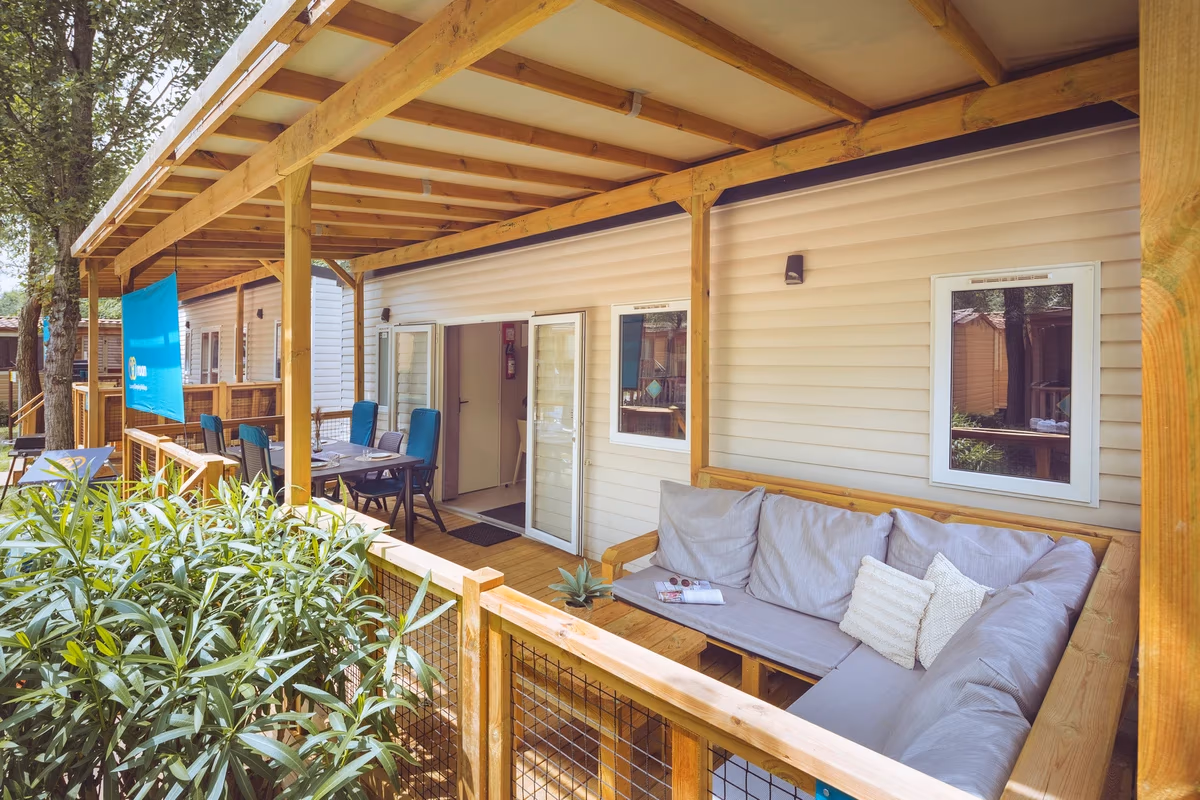 Loungebank en eettafel op de overdekte veranda van een stacaravan op Camping Bijela Uvala, met oleanders langs het terras