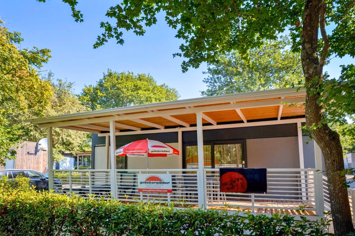 Moderne stacaravan met plat dak en een overdekt terras met parasol en buitentelevisie op Camping Bijela Uvala
