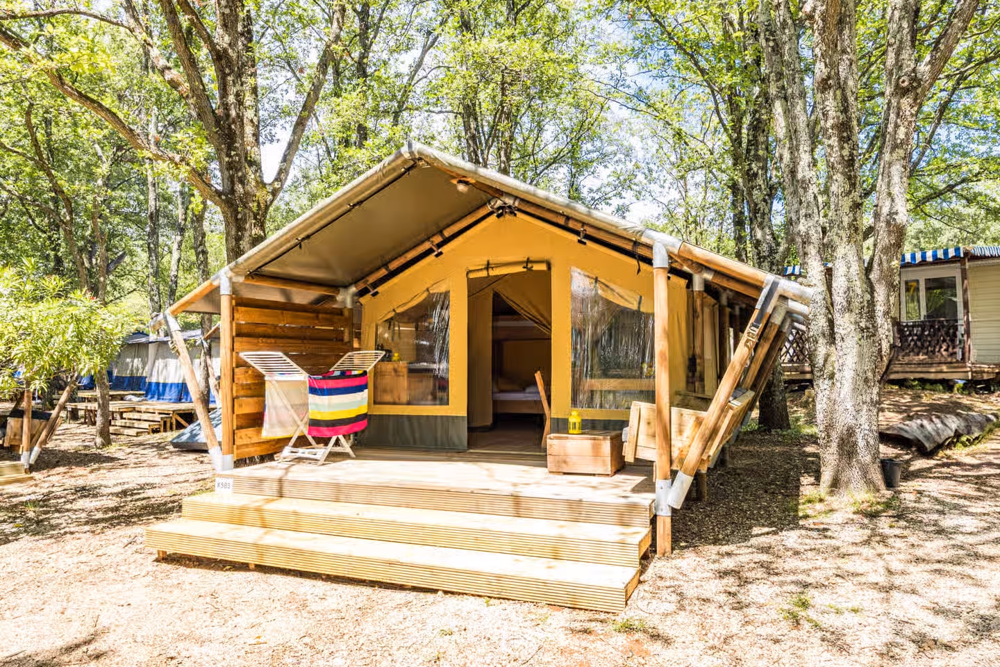 Safaritent met puntdak en een houten trap naar het terras op Camping Bijela Uvala, met een handdoek op een wasrekje