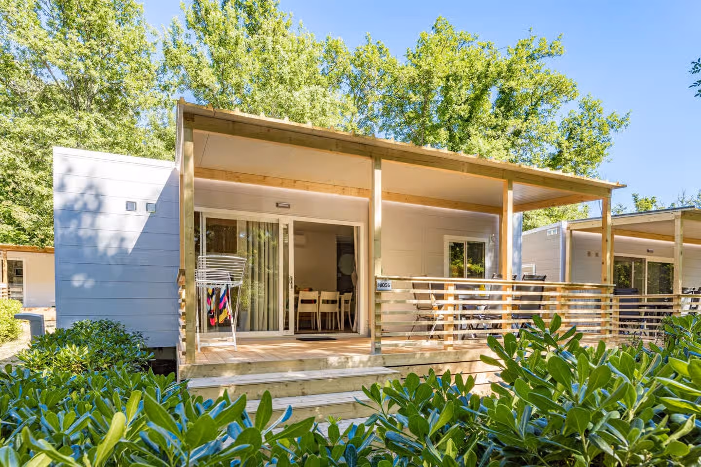 Stacaravan met een overdekt terras en schuifpui op Camping Bijela Uvala, met een wasrek met handdoeken en oleanders ervoor