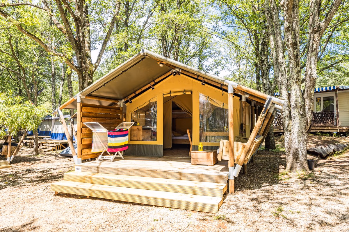 Safaritent met een puntdak en een houten trap naar het terras op Camping Bijela Uvala, met een gekleurde handdoek op een wasrekje
