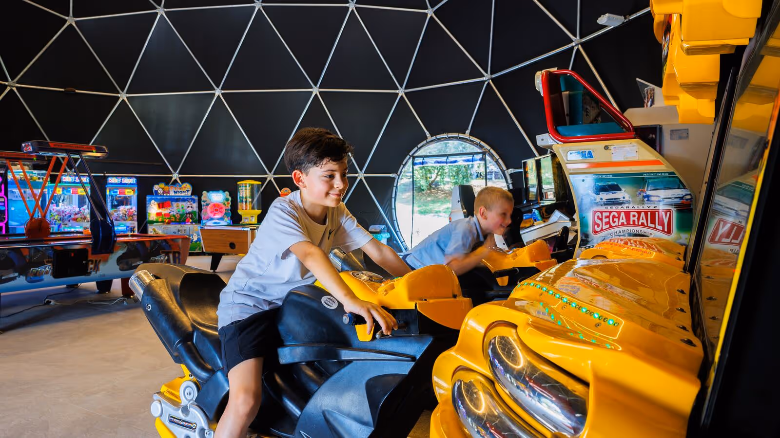 Gezin speelt samen bij een racemachine in de speelhal van Camping Bijela Uvala
