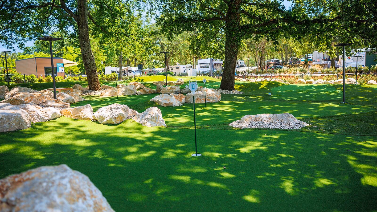 Schaduwrijke minigolfbaan met kunstgras en natuurlijke rotsen op Camping Bijela Uvala