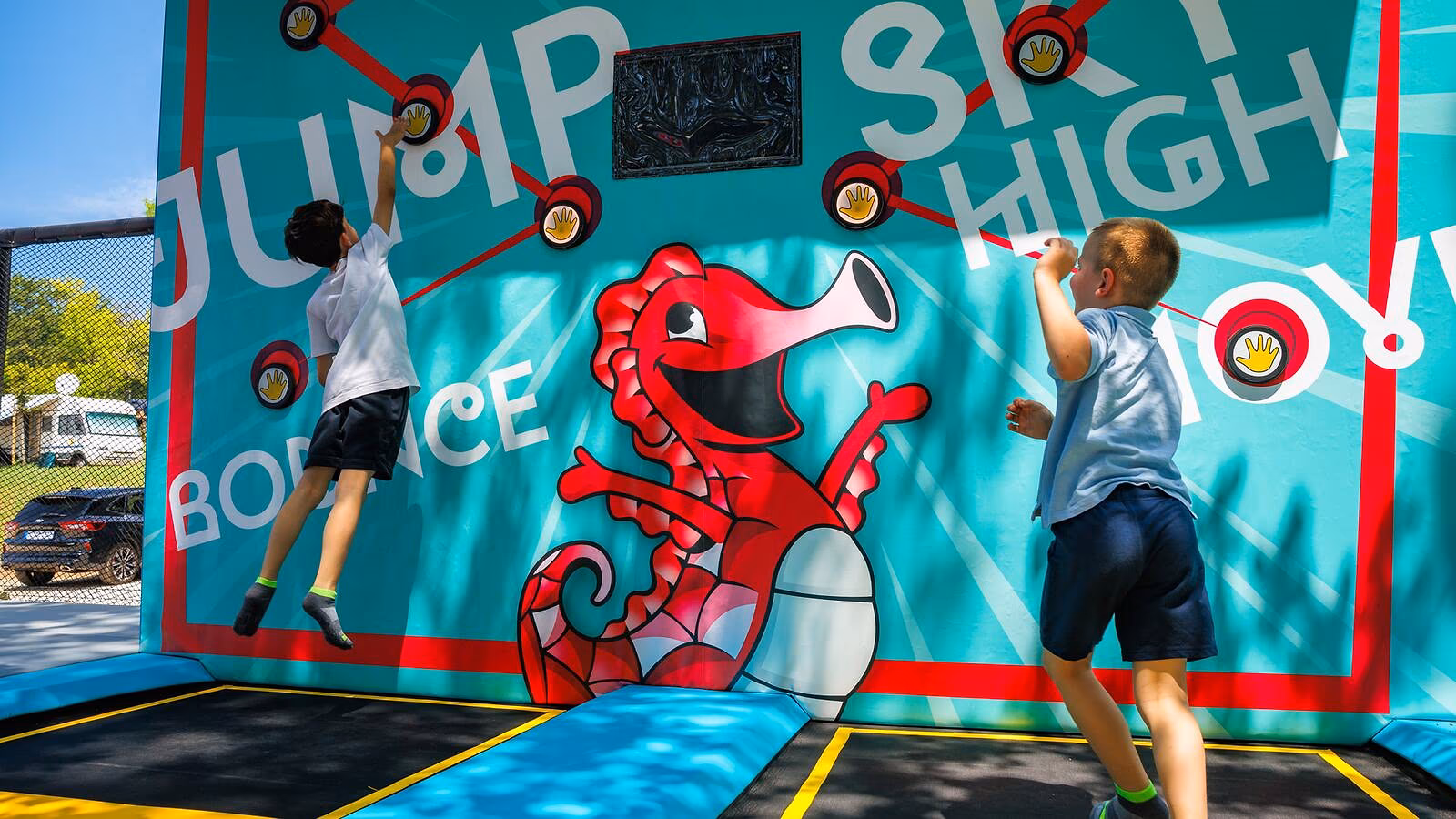 Kind springt tegen een kleurrijke wand bij de Jump High-activiteit op Camping Bijela Uvala