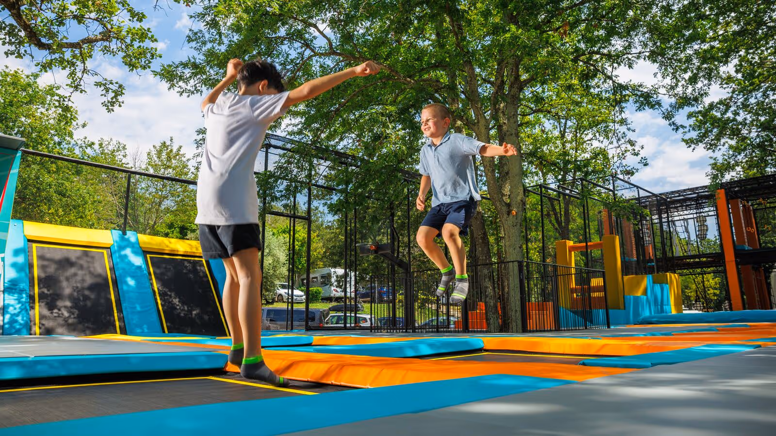 Twee kinderen springen op een trampoline tussen de bomen op Camping Bijela Uvala