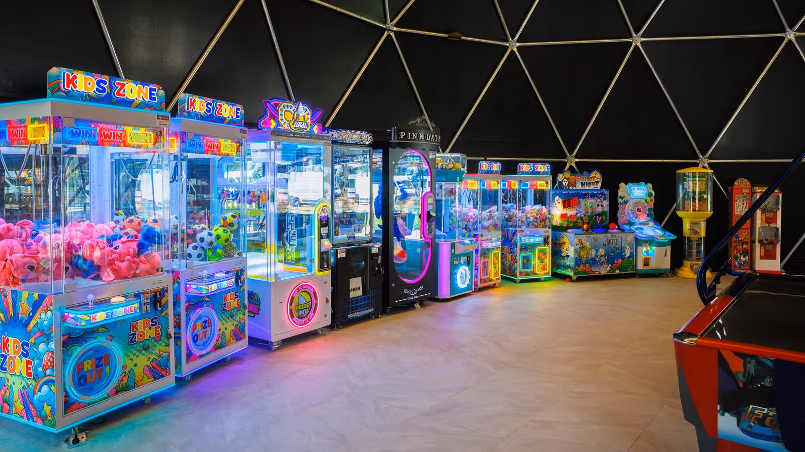 Rij kleurrijk verlichte arcademachines in de speelhal van Camping Bijela Uvala