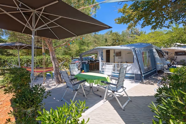 Luxury staanplaats van Camping Bijela Uvala met caravan, parasol, hangmat en groen terras