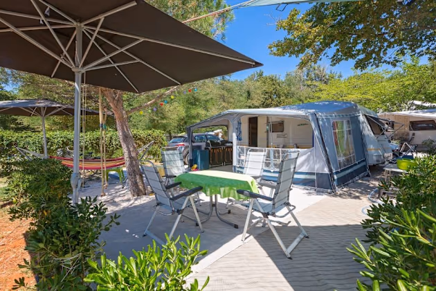 Luxury staanplaats van Camping Bijela Uvala met caravan, parasol, hangmat en groen terras
