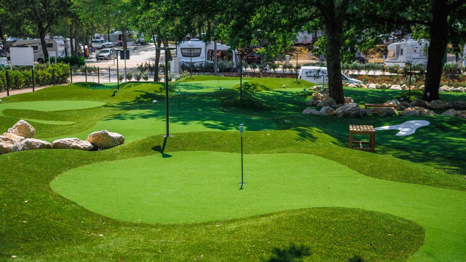 Groene minigolfbaan met heuvels en stenen tussen de bomen van Camping Bijela Uvala