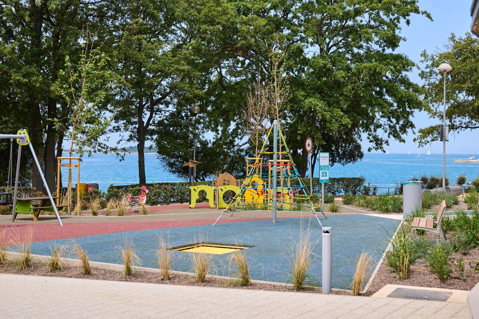 Kinderspeelplaats tussen de bomen met uitzicht op zee, Camping Bijela Uvala