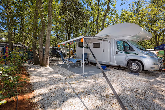 Superior Mare staanplaats van Camping Bijela Uvala met camper, zonnescherm en lichtslinger op wit grind