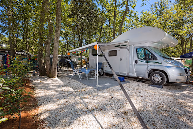 Superior Mare staanplaats van Camping Bijela Uvala met camper, zonnescherm en lichtslinger op wit grind