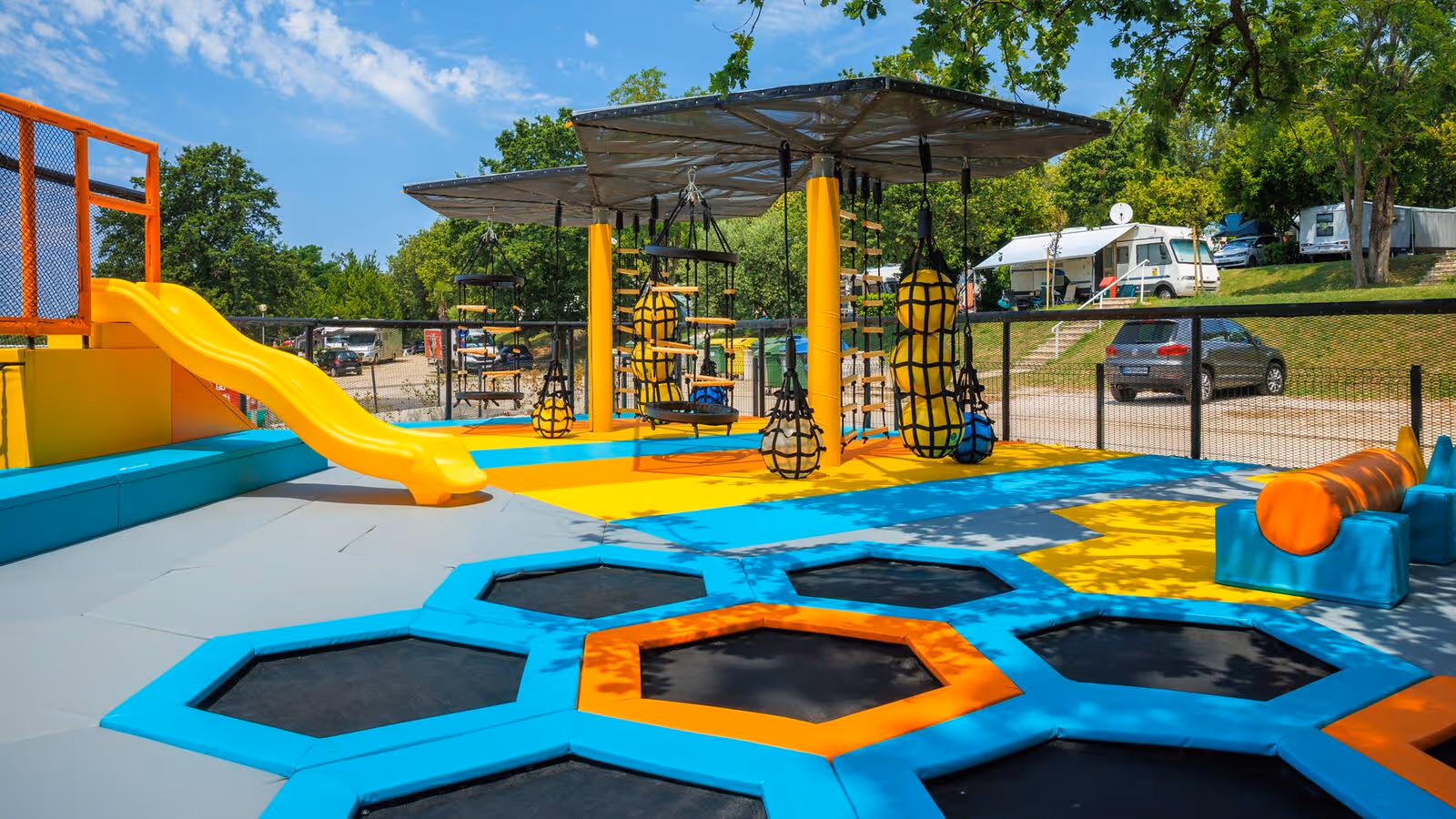 Speelzone met trampolines, een gele glijbaan en klimtoestellen op Camping Bijela Uvala