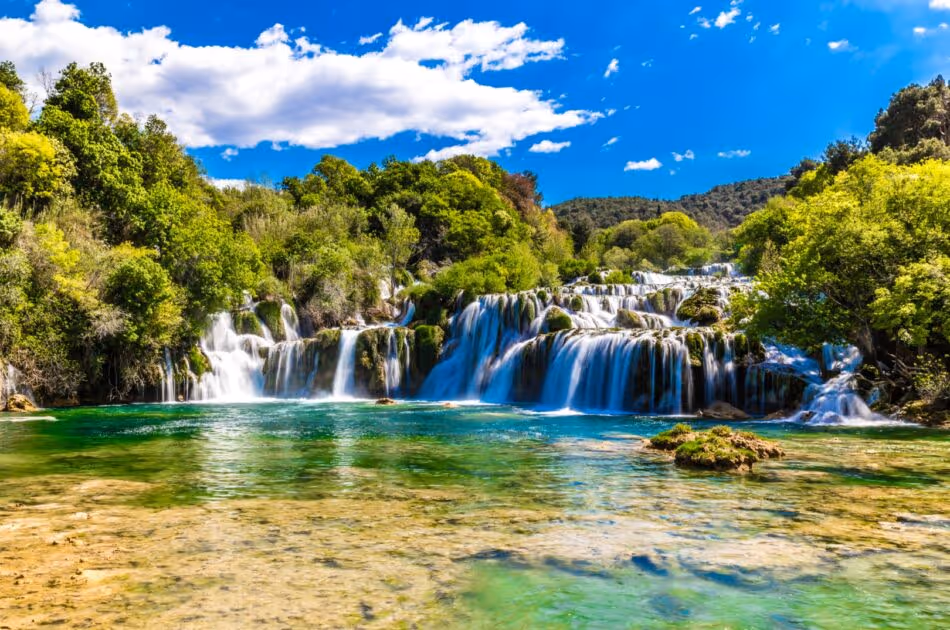 Watervallen van Nationaal Park Krka die over begroeide terrassen in turquoise water vallen