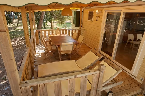 Overdekt houten terras van een Premium mobile home op Camping Bijela Uvala met eettafel en twee ligbedden