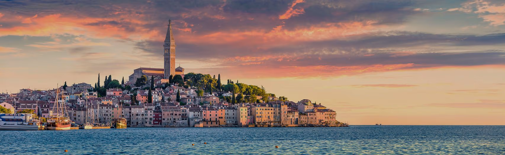 Rovinj in avondlicht gezien vanaf het water, met vissersboten voor de gekleurde gevels